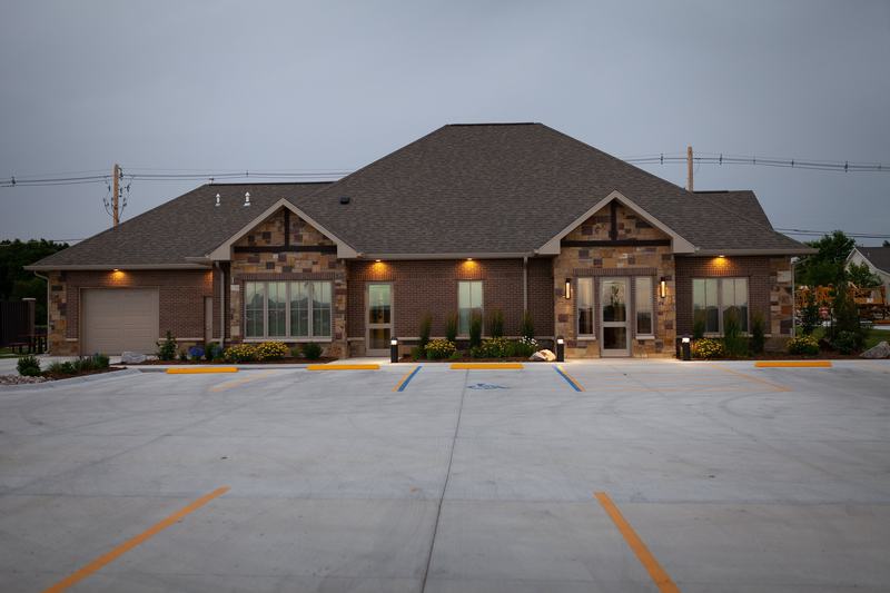 Exterior view of Owen Oral & Implant Surgery building at dusk, featuring a single-story medical facility with stone and brick architecture and empty parking lot.