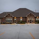 Exterior view of Owen Oral & Implant Surgery building at dusk, featuring a single-story medical facility with stone and brick architecture and empty parking lot.