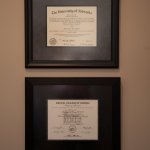 Two framed professional certificates and credentials displayed on beige wall in the office.