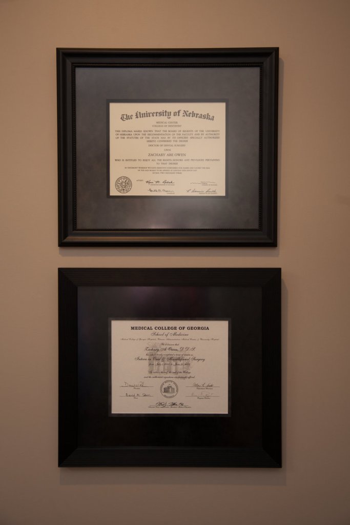 Two framed professional certificates and credentials displayed on beige wall in the office.
