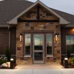 Front entrance of Owen Oral & Implant Surgery showcasing decorative stone and brick facade with glass doors and warm exterior lighting.